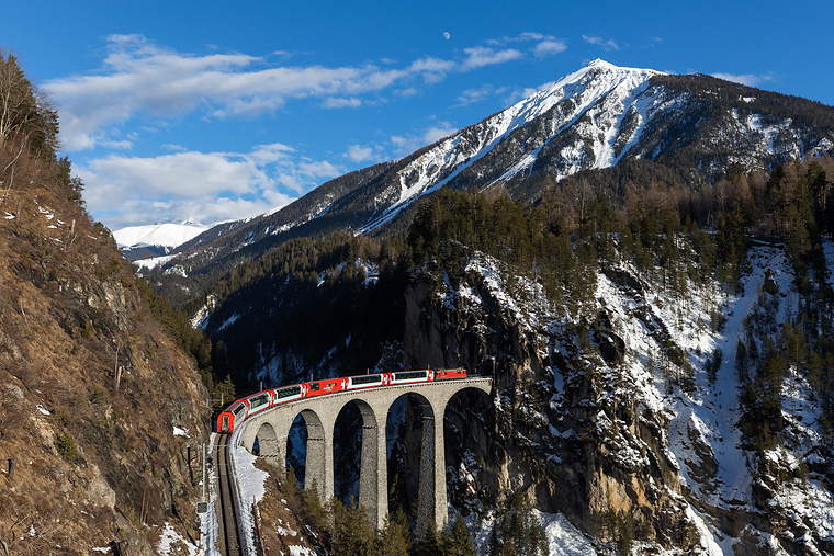 A panoramic train crossing an alpine viaduct